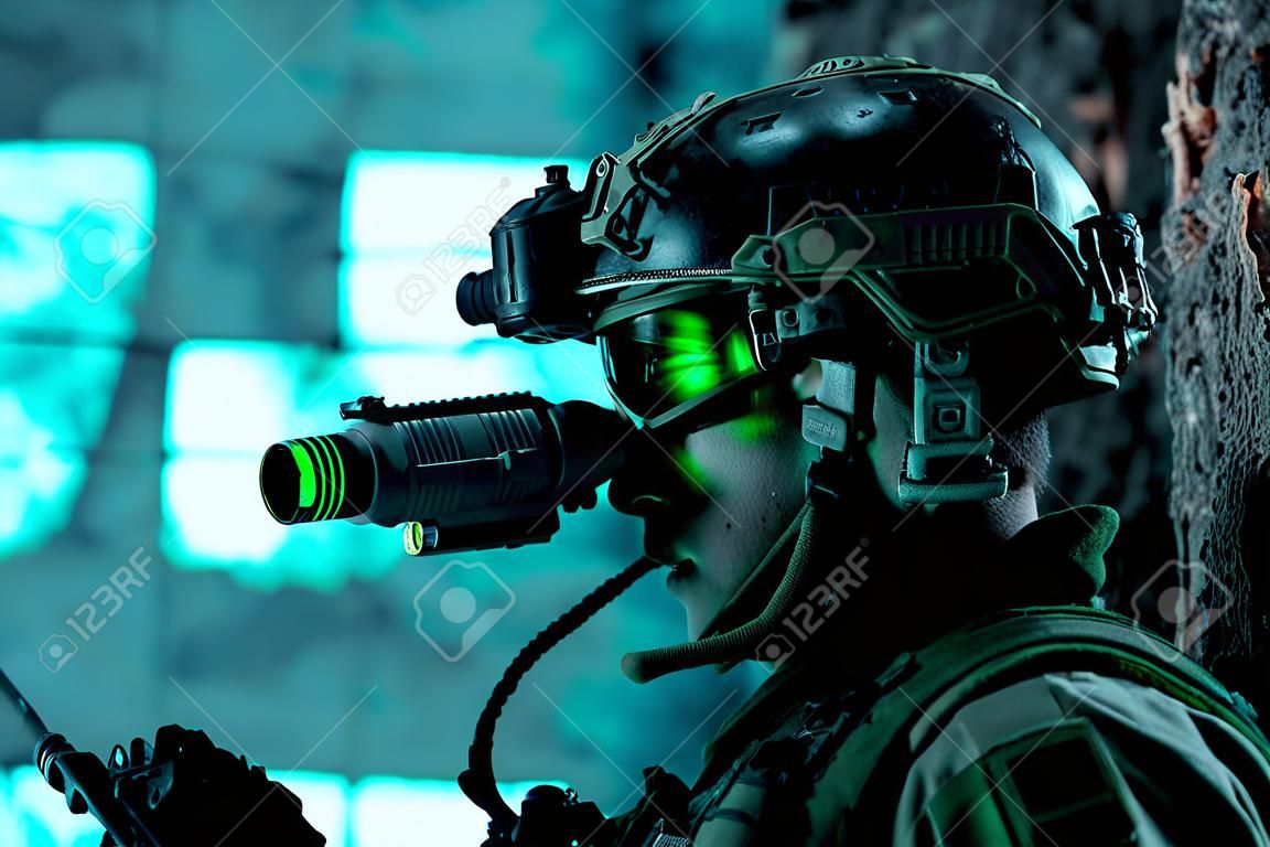 Nahaufnahmemannuniform mit Maschinengewehr und eingeschaltetem Nachtsichtgerät. Airsoft-Soldat mit grünem Licht im Gesicht im Nachtgebäude. Seitenansicht.