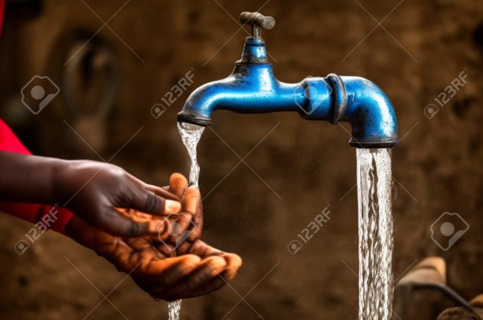 African child reaching for water under a tap as a symbol for water scarcity in African countries