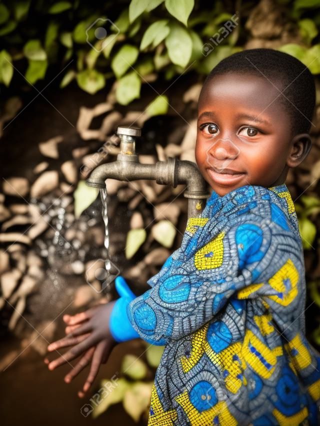 Jeune garçon africain tenant la main sous un robinet. Les problèmes de pénurie d'eau concernent l'accès insuffisant à l'eau potable. 1 milliard de personnes dans le monde en développement n'y ont pas accès.