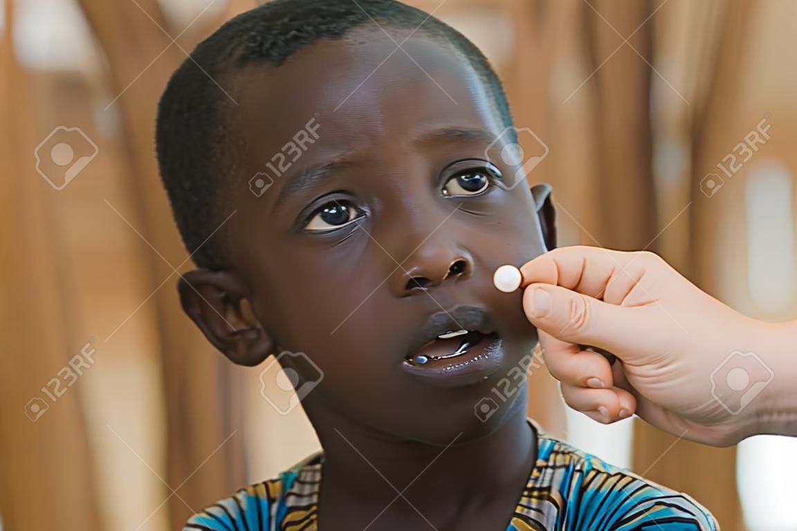 Biały lekarz dając pigułkę do małego afrykańskiego chłopca