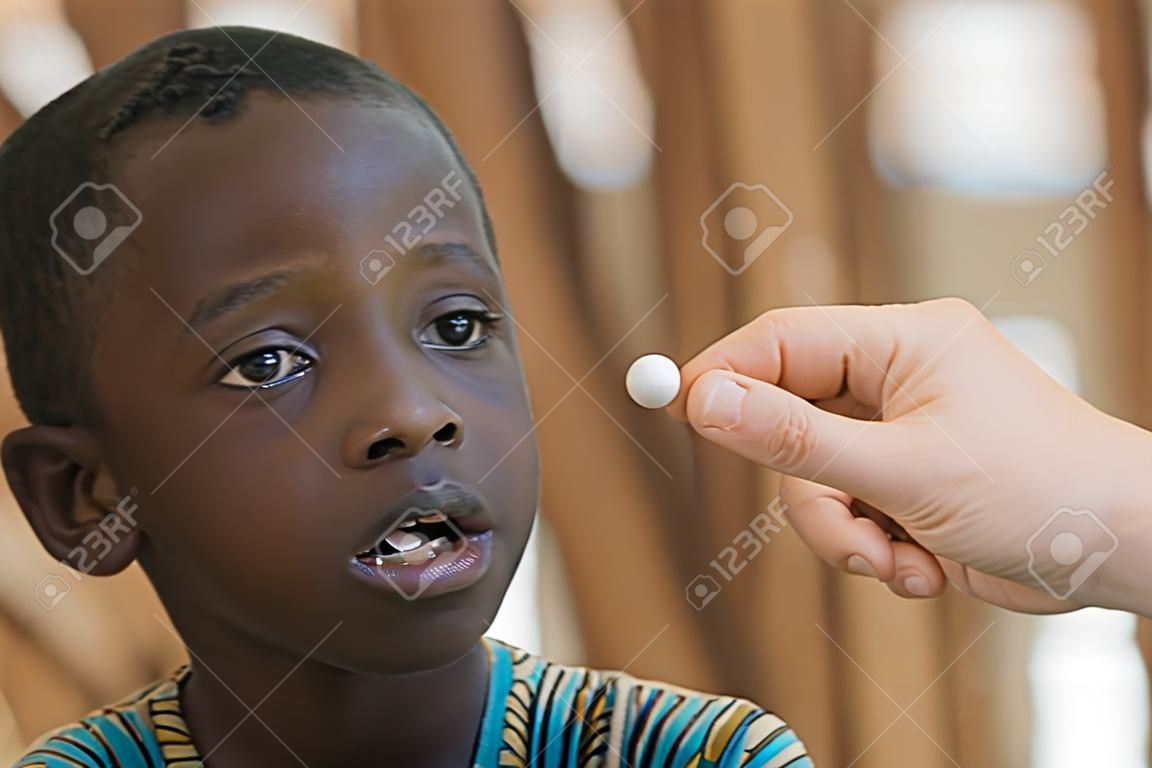 Biały lekarz dając pigułkę do małego afrykańskiego chłopca
