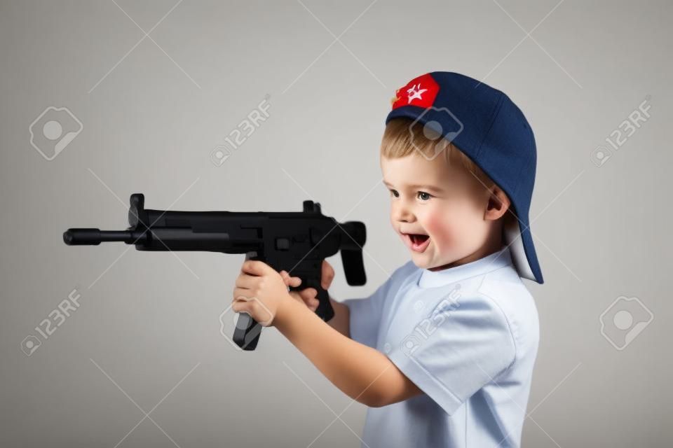 Little boy plays with gun on a white background