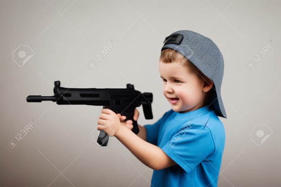 Little boy plays with gun on a white background