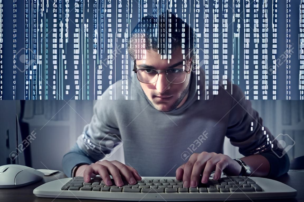 Jeune homme à taper sur un clavier d'ordinateur en face d'un écran