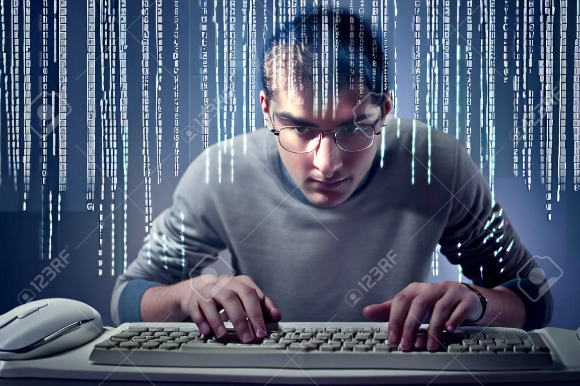Young man typing on a computer keyboard in front of a screen