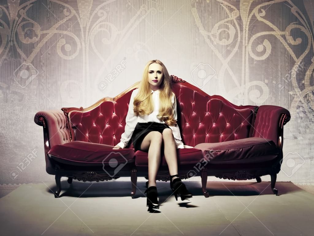 Bella donna ricca seduta su un divano di velluto