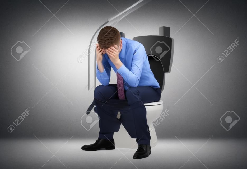 Estresado hombre de negocios joven en un inodoro con las manos en su pelo