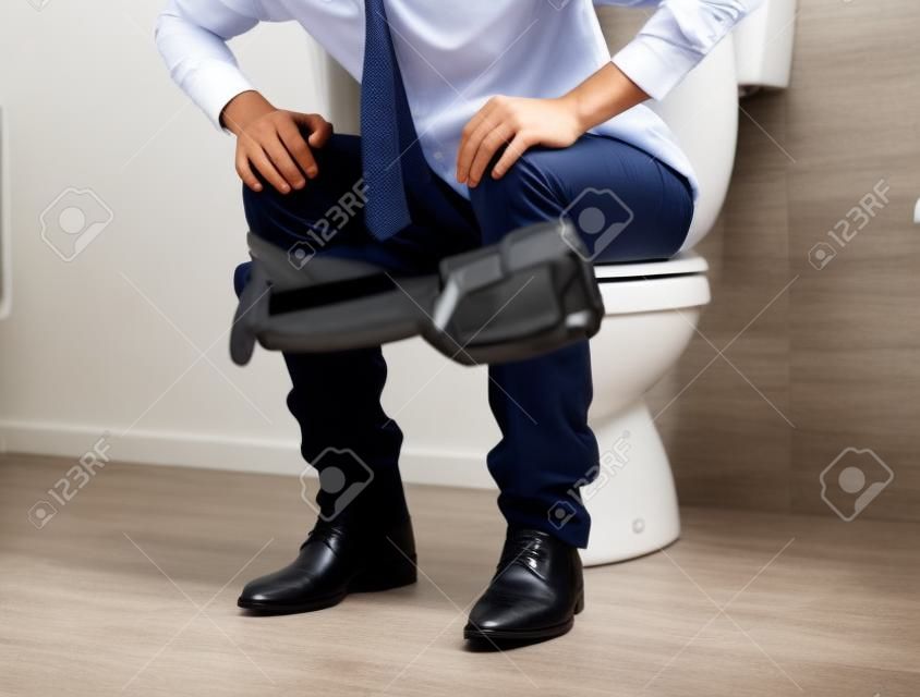 Jonge zakenman op het toilet legt zijn handen op zijn knieën
