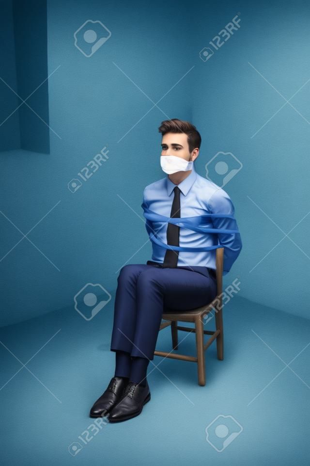 Hombre de negocios joven atado a una silla y amordazada en un sótano