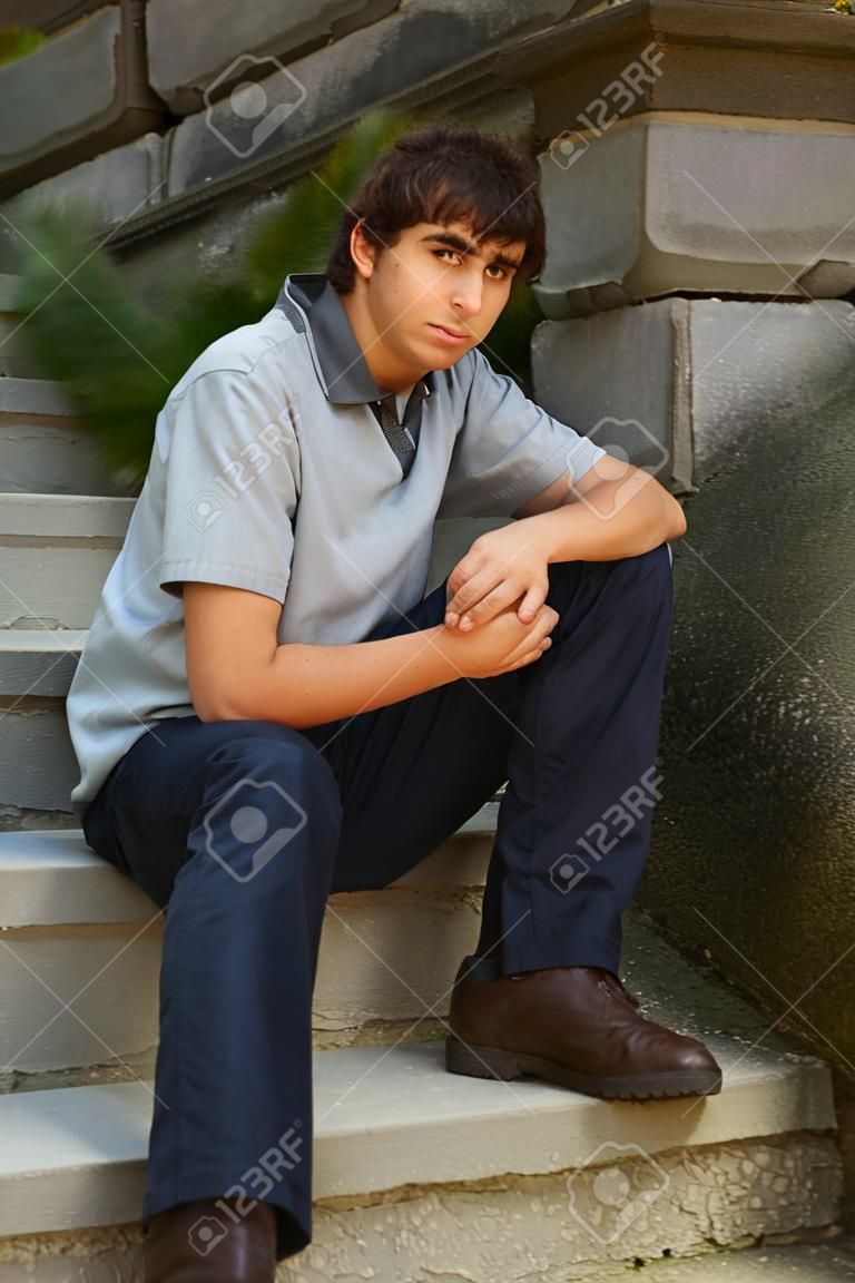 Young adult man sitting on stone stairs