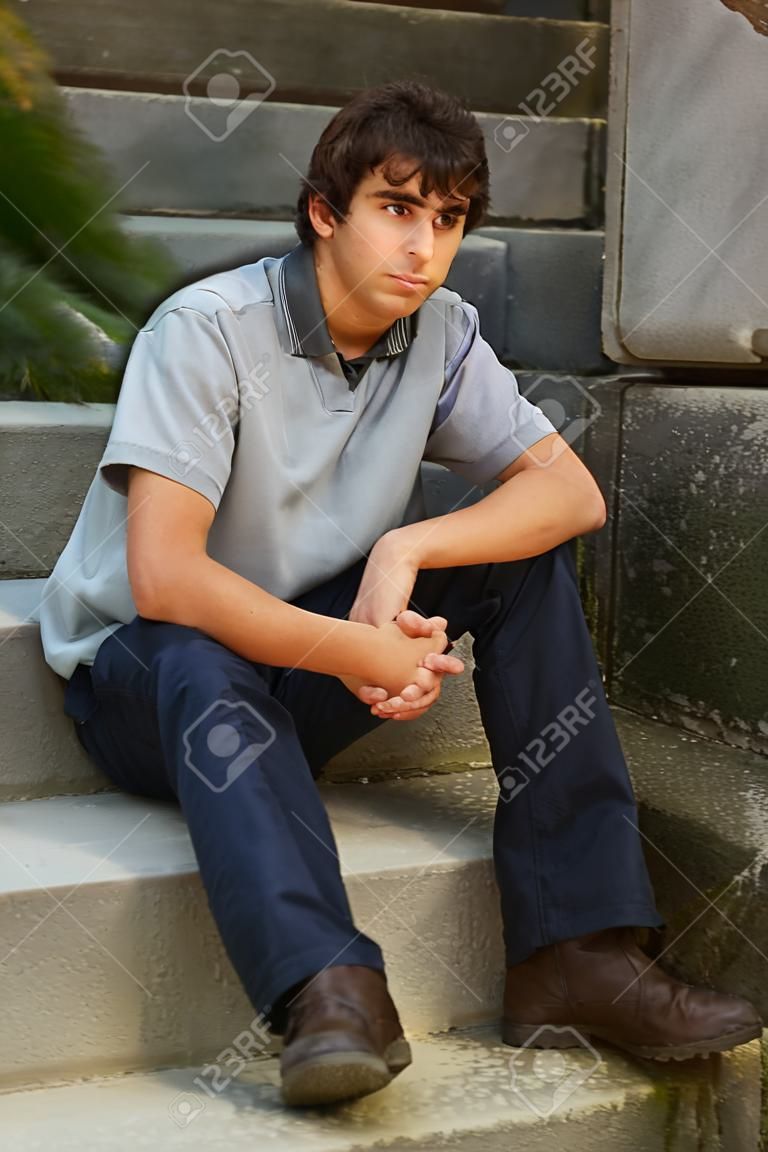 Young adult man sitting on stone stairs