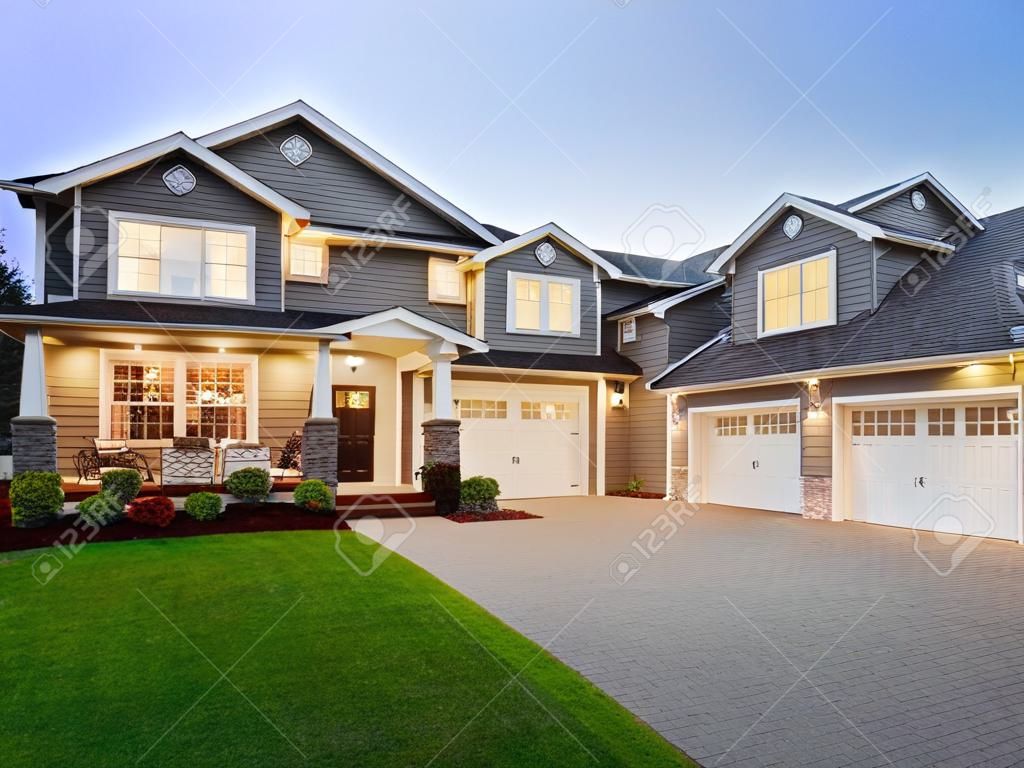 home exterior at night/twilight with beautiful green grass three-car garage, and driveway