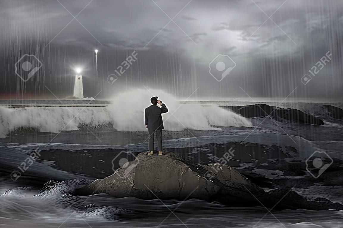 L'uomo sulla roccia guardando faro nel mare con la tempesta, tuoni, alleggio e le onde nel buio
