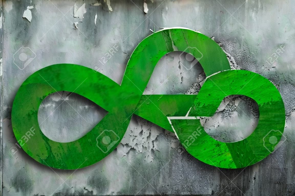 Green Eco-friendly and circular economy concept. Infinity arrow recycling symbol with green grass texture on dirty concrete wall background.