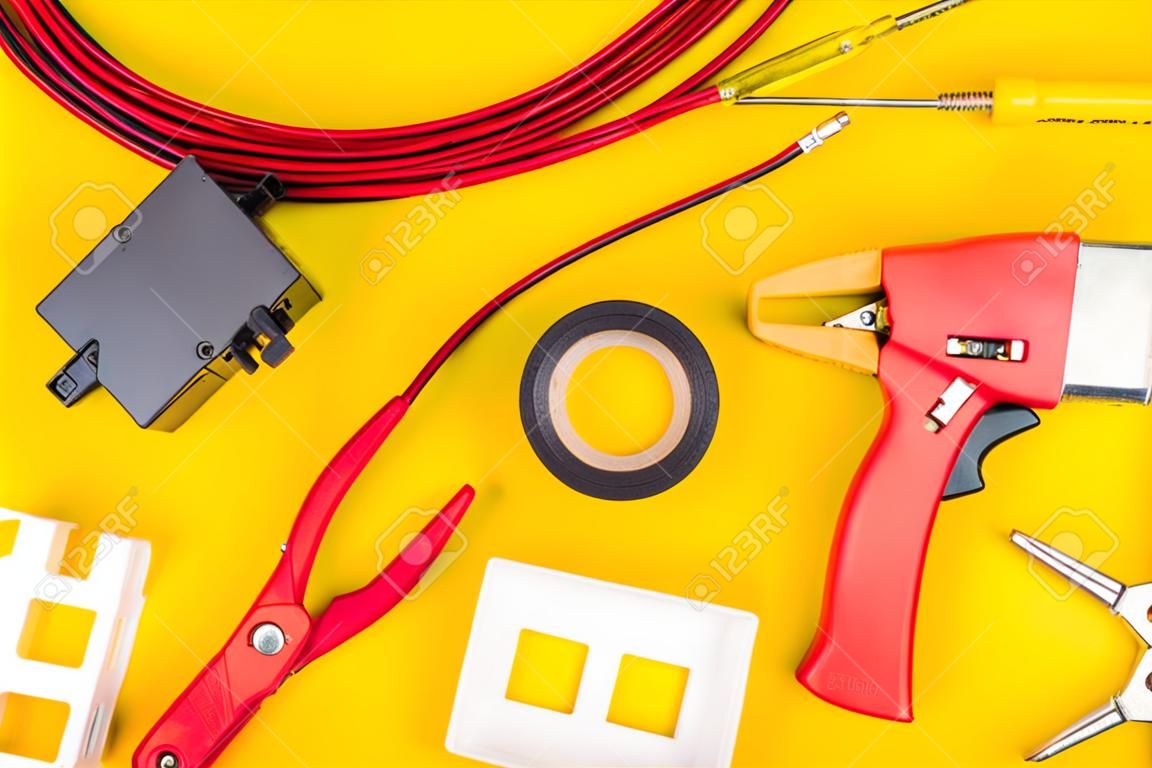 Different electrician's supplies on yellow background. Background of professional electrician tools with space for text.electrician concept home electrical repair technician.