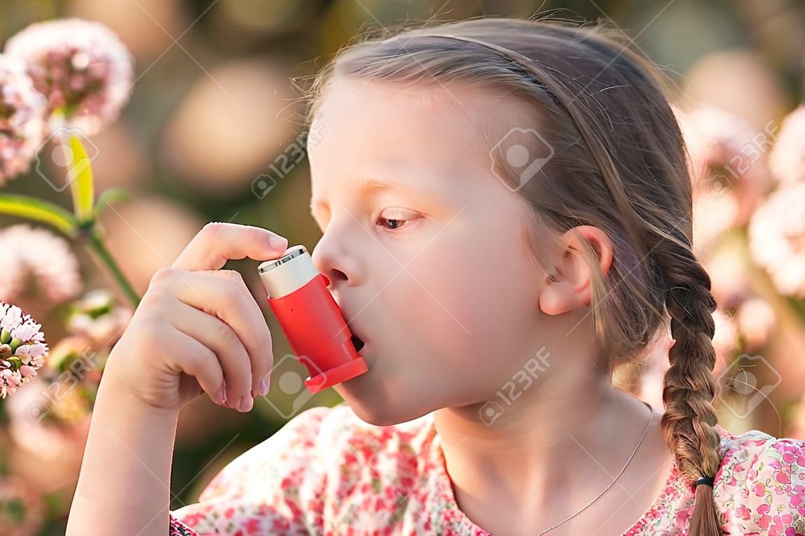 Little girl having asthma using asthma inhaler due to pollen allergy - shallow depth of field