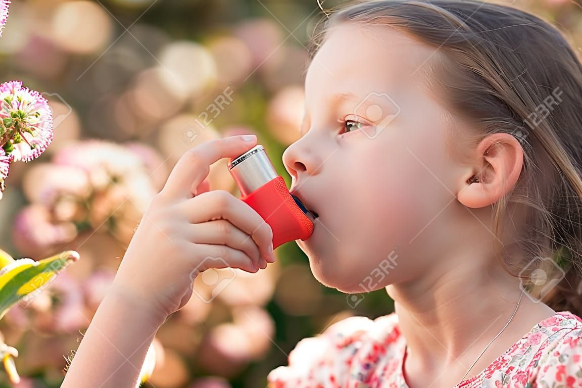 Menina que tem a asma que usa o inalador da asma devido à alergia do pólen - profundidade rasa do campo