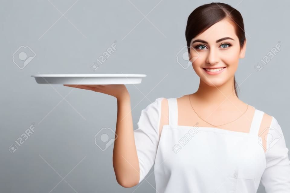 Jovem mulher atraente segurando uma bandeja vazia isolada no fundo branco.