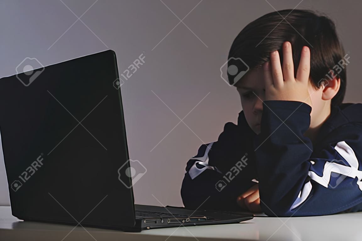 Maschera del primo piano del ragazzo adolescente di bullismo che si sente sconvolto davanti al computer. Il ragazzo triste stressato sta facendo il prepotente con i suoi compagni di classe.