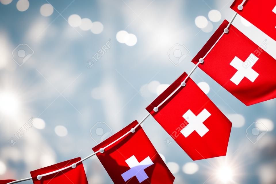 A garland of Switzerland national flags on an abstract blurred background.