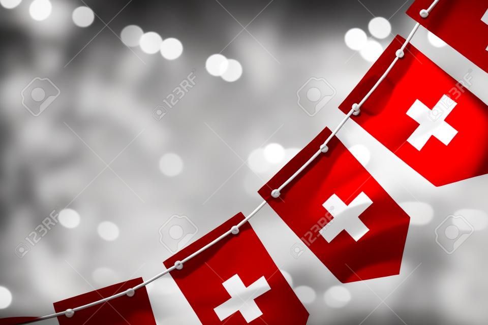 A garland of Switzerland national flags on an abstract blurred background.