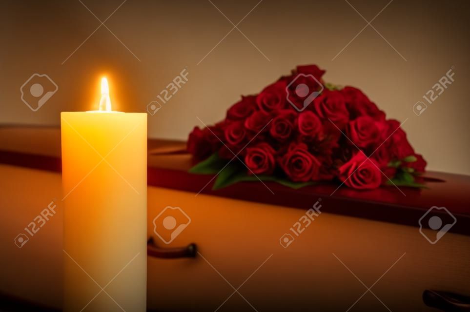 Горящая свеча с гробом и цветочной композиции на фоне в морг