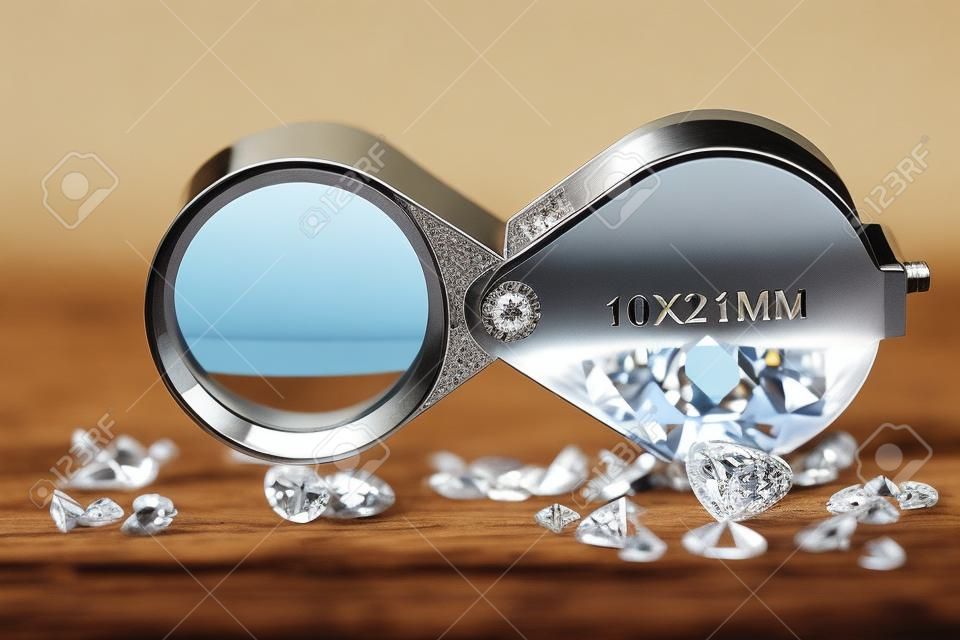 brilliant cut diamonds with folding magnifier on wooden background
