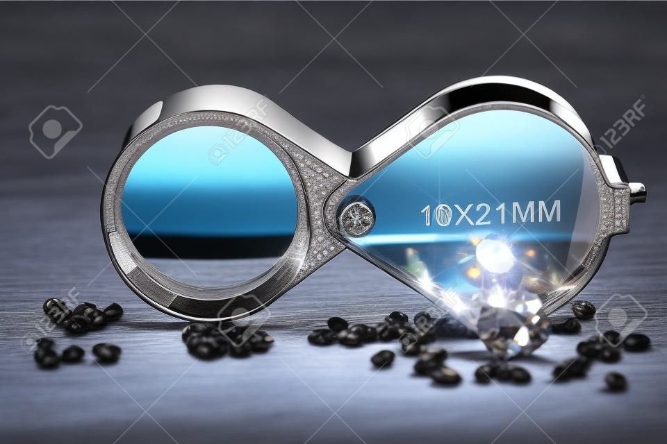 brilliant cut diamonds with folding magnifier on wooden background
