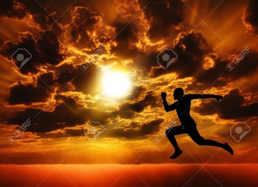 Silhouet van de mens rennen naar de zon op bewolkte achtergrond