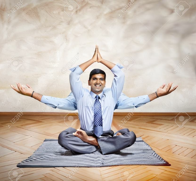 Happy Indian businessman with many hands doing yoga in the office 