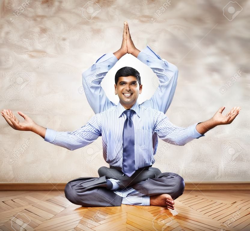 Happy Indian businessman with many hands doing yoga in the office 