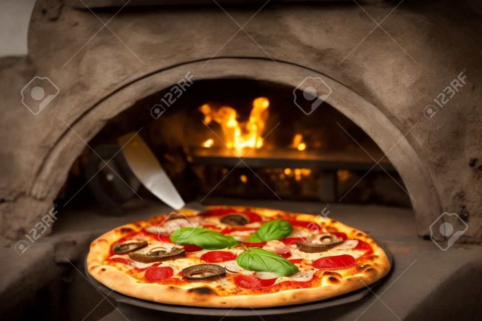 Close Delicious Italian pizza in a shovel putting in wood burning oven