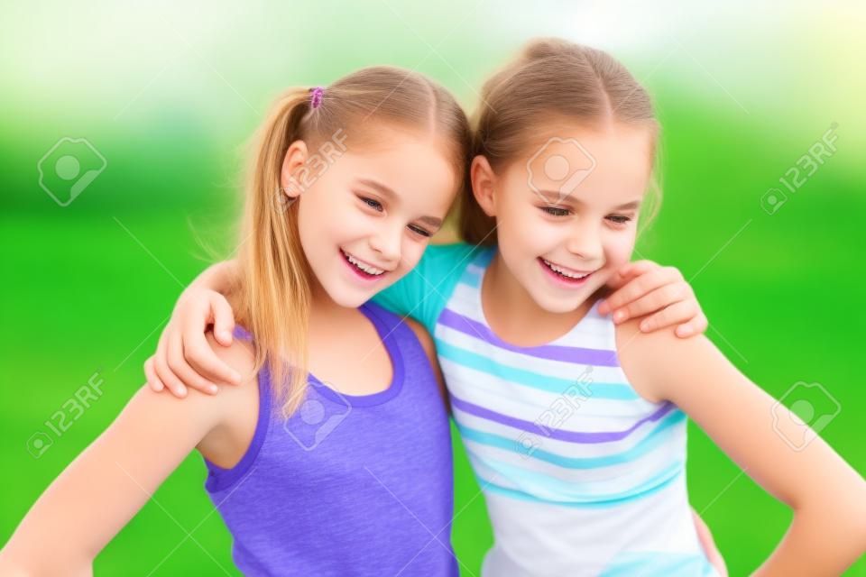 Feliz pré-adolescentes meninas amigável abraçando no fundo de grama verde