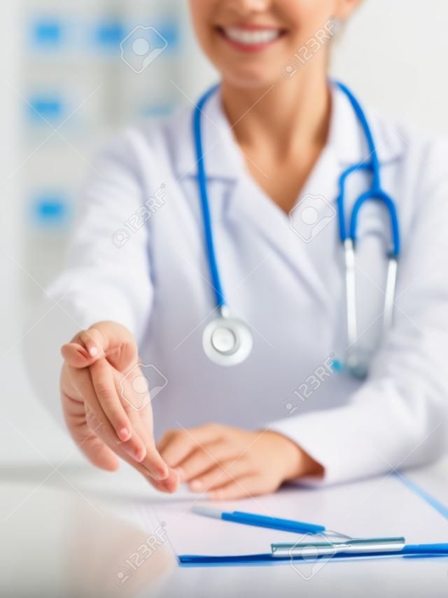 Médico de medicina feminina oferecendo mão para aperto de mão de perto. Parceria e conceito de confiança.