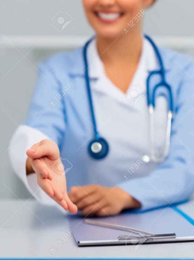 Médico de medicina feminina oferecendo mão para aperto de mão de perto. Parceria e conceito de confiança.