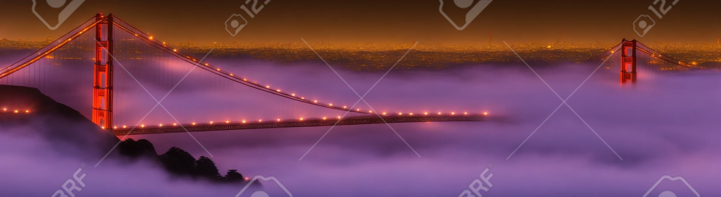 霧は夕暮れ時にゴールデン ゲート ブリッジをロールバックします。San Francisco の街は、バック グラウンドで。パノラマの組成物。