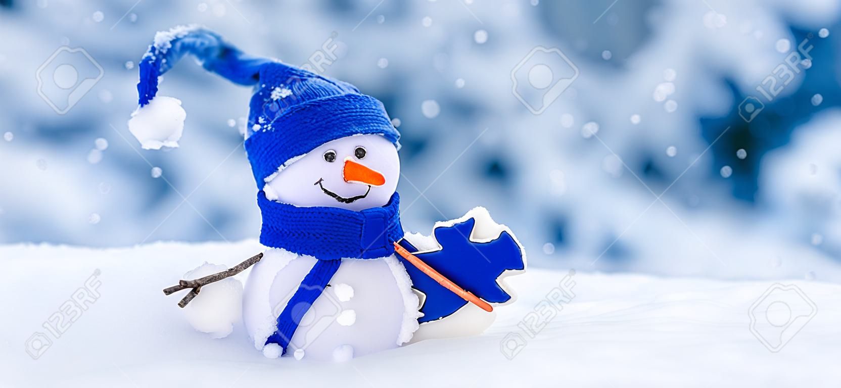 Little handmade snowman on the white snow on blue background.