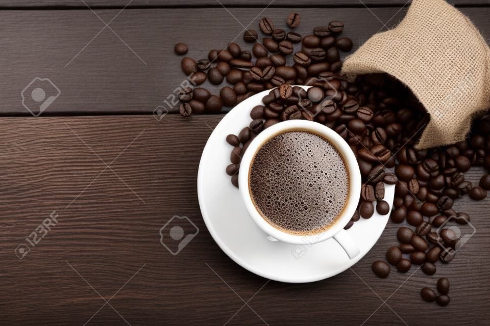 Kahve fincanı ve ahşap zemin üzerine kahve çekirdekleri. Üstten görünüm.