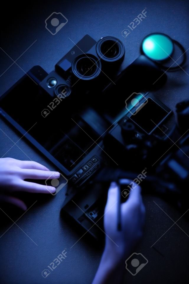Postazione fotografica digitale su sfondo nero. Vista dall'alto di fotocamera digitale, flash, obiettivo e laptop.