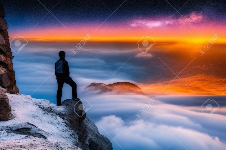 Man on top of a mountain standing contemplates the dawn