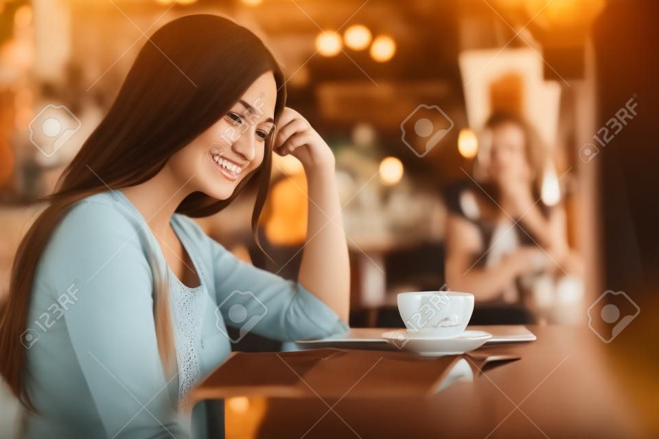 Porträt einer lächelnden Frau, die im Vintage-Café Kaffee trinkt.