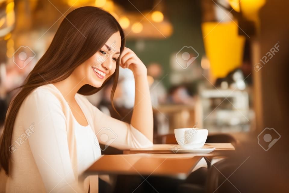 Porträt einer lächelnden Frau, die im Vintage-Café Kaffee trinkt.