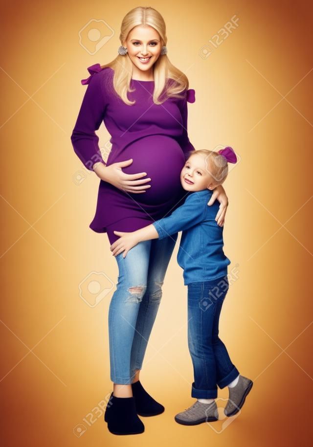 彼女の小さな女の子の子供と妊娠中のブロンドの女性。幸せな家族