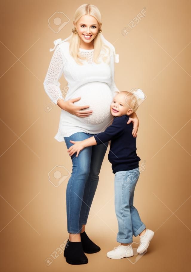 彼女の小さな女の子の子供と妊娠中のブロンドの女性。幸せな家族