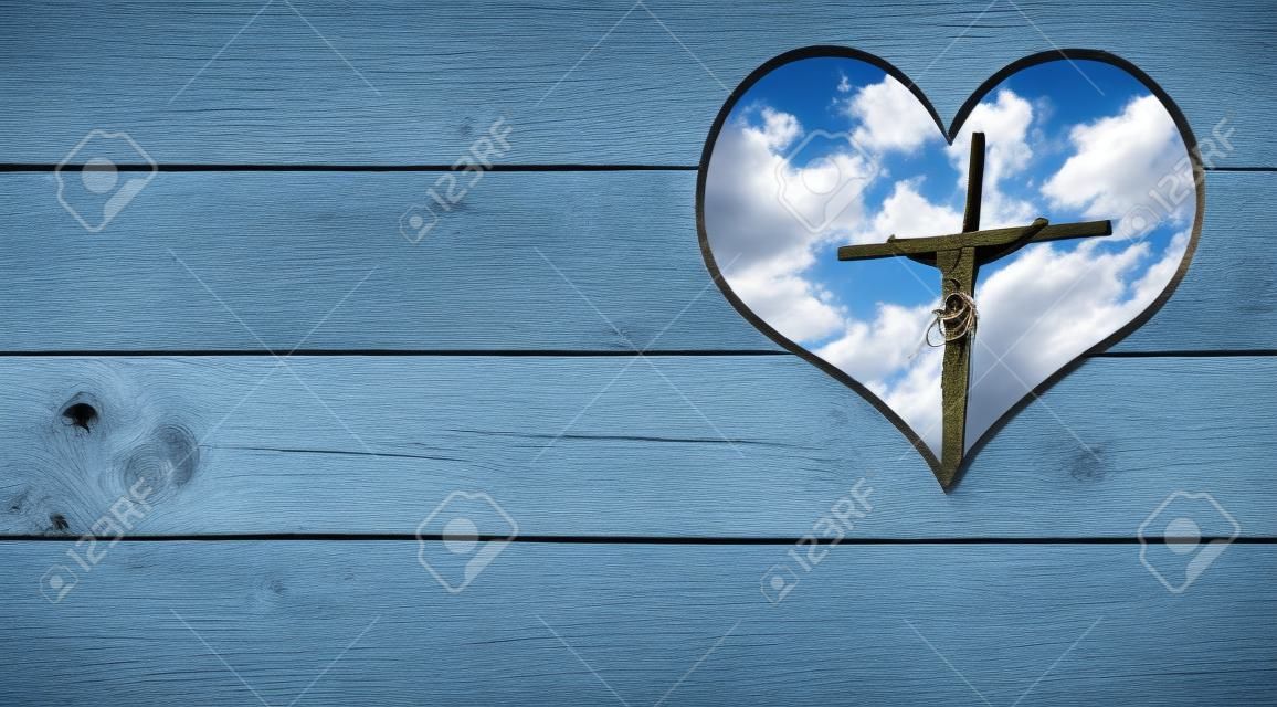 十字架のイエスとハートの形の穴と木製の壁と青い空と雲