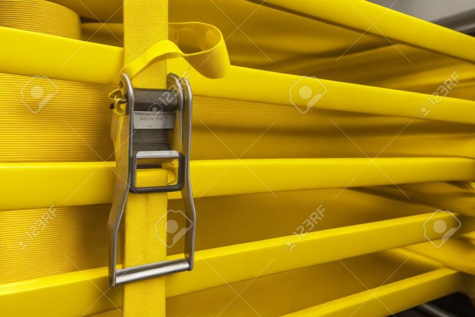 Objects fixed by yellow ratchet strap. Concepts of firm, strong, and stable.