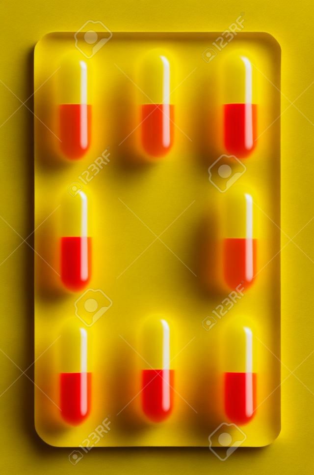 Одной таблетки желтого и красного капсулы, изолированных в белом фоне
