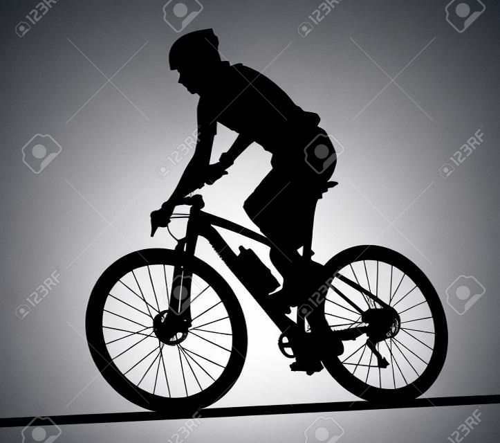 Side profile silhouette of male mountain bike racer riding bicycle