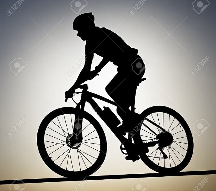 Side profile silhouette of male mountain bike racer riding bicycle