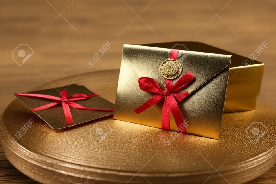 Geschenkgutschein, Geschenkgutschein oder Rabatt. Nahaufnahme eines bronzenen Einladungsumschlags mit einem Band und einem Wachssiegel, einem Geschenkgutschein, einer Karte, einer Hochzeitseinladungskarte
